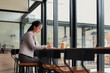 © jojo - Young woman sitting and working in a cafe