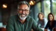 © Larisa AI - A gray-haired man with glasses smiles warmly at the camera, exuding confidence and wisdom in a welcoming environment filled with soft lighting and friendly faces.