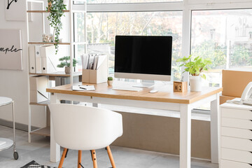 Wall Mural - blank computer monitor with folders and plants near window in office