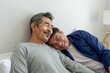 © Kawee - Asian elderly male gay couple lying down on bed and hugging each other.
