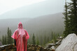 © Cavan Images - Tourist in poncho overlooks foggy pines in Banff National Park, Canada