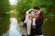 © khmelev - family outdoor portrait with nature backdrop, happy couple and child by serene lake in lush green park, capturing joyful bonding moment, perfect for family lifestyle promotions