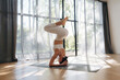 © standret - Upside down, headstand. Young woman in fitness clothes is in the room