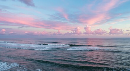 Wall Mural - Serene Sunset Ocean View - Peaceful ocean scene at sunset with soft pink and purple clouds. Calm waves gently roll onto the shore