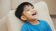 © Luna - A young child sitting on a chair with a joyful expression, smiling at something