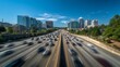 © Plaifah - A wide-angle view of a bustling expressway with fast-moving traffic, modern city buildings in the background, and a bright blue sky overhead