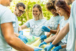 © Davide Angelini - Group of volunteer cleaning picking up plastic litter in the park - Diverse group of people collect trash in the forest - Environmental protection, non profits organization and save the planet concept