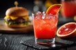 © LimeSky - Beverages and meal Red citrus drink with orange grapefruit ice and a burger on a dark wooden table