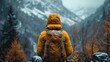 © svastix - A solitary hiker clad in a bright yellow jacket stands before majestic mountains, capturing the essence of adventure and the beauty of nature in winter's embrace.