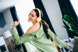 © deagreez - Young woman wearing headphones enjoys music at home while smiling and dancing in a beautifully styled interior living space.