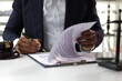 © Wasan - Lawyer reading legal documents and preparing to sign a contract. Lawyer is carefully reviewing legal documents at his desk.