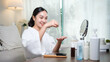 © wattana - Happy young woman in white robe using hydrogel eye patch for dark circle treatment. Self care concept.