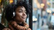 © VladyslavS - A curly-haired woman with headphones looks out the window with a dreamy expression.