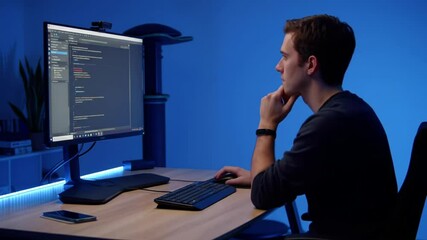 Man Coding On Computer In Dark Room With Blue Light