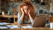 © svastix - This image portrays a frustrated young woman holding her head in despair, surrounded by paperwork and a laptop, representing the high stresses of modern work life.