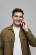 © muse studio - Smiling young man engaged in a lively phone conversation against a neutral background in a contemporary setting