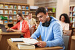© New Africa - People studying at desks in public library, selective focus