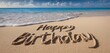 © Muhammad Muqeet - Happy birthday message written in sand on a beach with ocean waves approaching the shoreline view