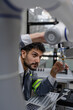 © Nassorn - Latino robotic development engineer working robot arm connection control at electronic futuristic science laboratory. Hispanic technician learning innovation machine in automated engineering academy.