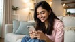 © Jo - Indian girl from India smiling while reading messages on phone in living room