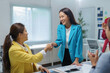 © amnaj - Asian businesswomen shaking hands after closing a deal, colleagues clapping hands celebrating success in the background