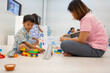 © themorningglory - Mom with kids boy and girl learnning build color toy block in classroom