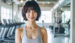 © doubledecker - モダンなフィットネスジムで笑顔を見せる日本人女性インストラクター – Smiling Japanese Female Fitness Instructor in a Modern Gym Setting