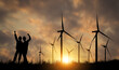 © ฺฺฺBoonterm - Silhouette two female engineers working outdoors wind turbine power station raising their fists to the sky in joy at the start of work in the morning at sunrise amidst a beautiful windmill field.
