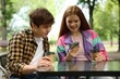 © New Africa - Teenage girl and boy with coffee and smartphone in outdoor cafe
