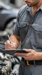 © lililia - Close-up of a mechanic taking notes on a clipboard while evaluating a vehicle in a well-lit garage setting