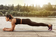 © New Africa - Sporty woman doing plank exercise on wooden pier near river