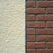 © Spot Decor - Close-up of textured off-white foam surface with bubbly, soft appearance contrasting sharply with rough, reddish-brown brick wall and granular gray grout, showcasing construction