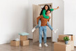 © Prostock-studio - Celebrating Moving Day. Happy couple celebrating relocation to their own home, cheerful guy giving lady piggyback ride, excited young millennial family of two having fun standing in new flat