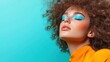 © svastix - A stunning model showcasing vibrant blue eyeshadow and bold curls against a bright aqua background, exemplifying creativity and modern beauty trends in makeup artistry.