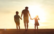© kieferpix - Father little children holding hands walking in a grass field into the sunset. Fatherhood, childhood family, parenting, fathers day concept