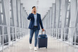 © Prostock-studio - Handsome Arab Man Walking With Suitcase In Airport And Talking On Cellphone, Young Middle Eastern Businessman Booking Transfer By Phone After Arrival, Enjoying Pleasant Conversation, Copy Space