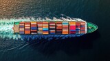 Aerial view of a large cargo ship sailing through the ocean, fully loaded with colorful shipping containers.