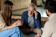 © Maria Vitkovska - Senior man receiving comforting support from family during therapy session