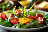 Fresh arugula and cherry tomatoes are topped with a vibrant yellow dressing being drizzled onto a healthy salad.