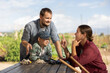 © JackF - Family of farmers has fun talking at a wooden table after work. Farmers rest after planting seeds and cultivating the land.