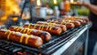 © zong - Grilled sausages with mustard drizzle cooking on an outdoor barbecue grill with smoke rising and a person holding a drink in the background