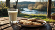 © Oksana - A glass of milk and a plate of cookies on a table against a nature background.