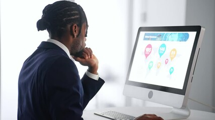 A black male business person working on a desktop PC in an office