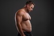 © digitalpochi - A muscular man, showing his belly and waistline after weight loss on a black background