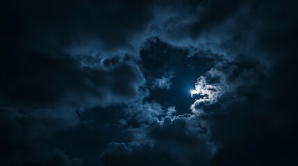 Canvas Print - moon partially hidden behind dark, dramatic clouds at night.