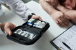 © pressmaster - Middle aged Caucasian man sitting at desk with male doctor showing diabetes monitoring kit including glucometer and insulin pen during medical consultation in clinic