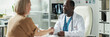© pressmaster - Middle aged Caucasian woman with glucose monitor on arm visiting Black male doctor in medical office, patient and physician shaking hands during diabetes consultation
