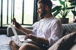 © BullRun - Young freelancer smiling while checking smartphone with laptop on knees, representing seamless digital flow and connected lifestyle of tech-savvy professionals working remotely.