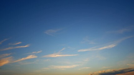 Wall Mural - a tranquil sunset sky timelapse with soft golden light illuminating wispy clouds over a clear blue b