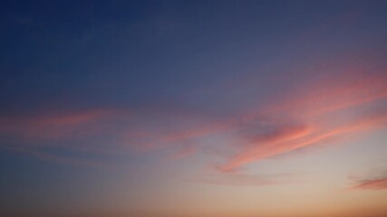 Wall Mural - a gentle sunrise sky timelapse with soft golden-orange clouds spreading across a calm blue backdrop,